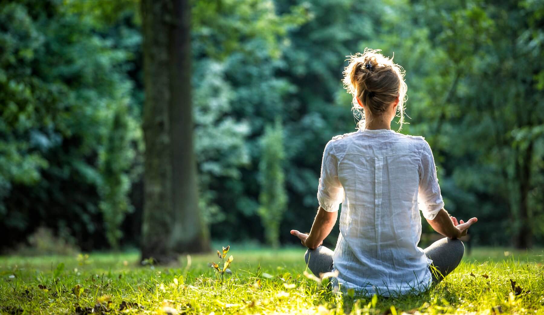 Young blonde woman meditating in the park